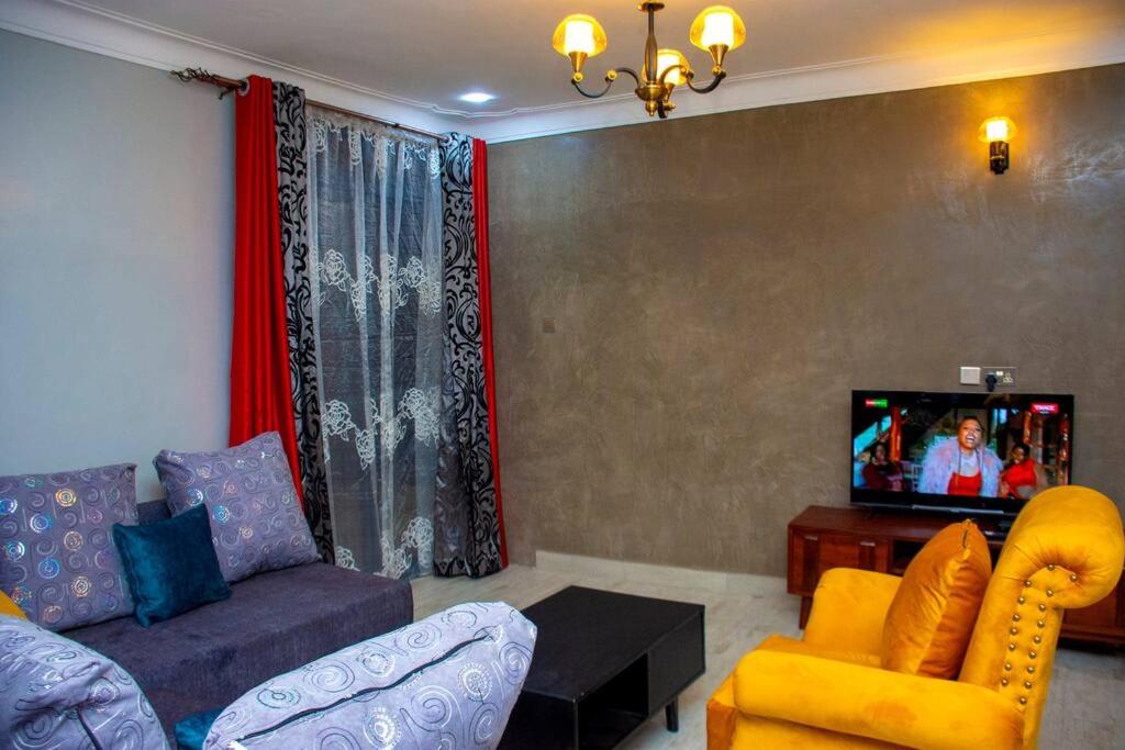 un soggiorno con divano e TV di Secure cozy getaway near Kampala business district a Kampala