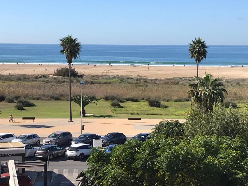 a parking lot next to a beach with palm trees and cars at CONIL frente a la playa Carril De la Fuente in Conil de la Frontera