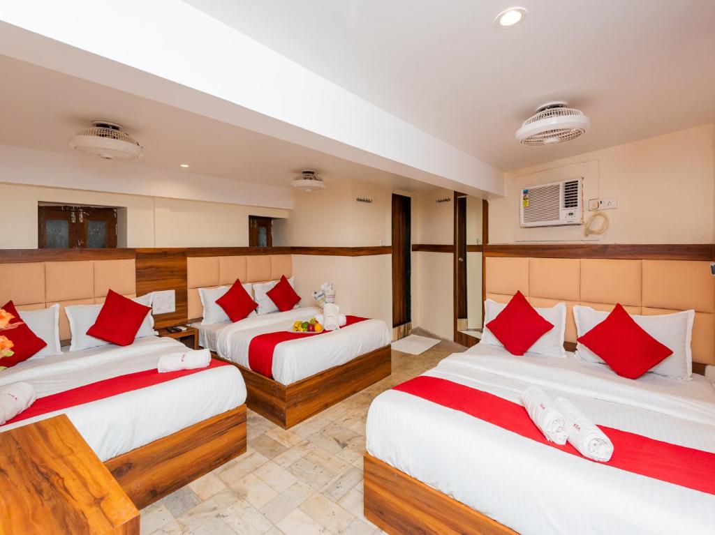 Habitación con 3 camas y almohadas rojas y blancas. en Hotel KGN - Mumbai en Bombay