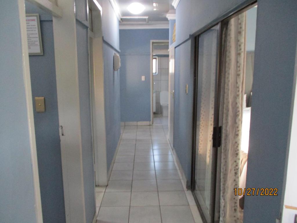 a hallway with blue walls and a white tile floor at PS GOOD TIME GUEST HOUSE in Klerksdorp