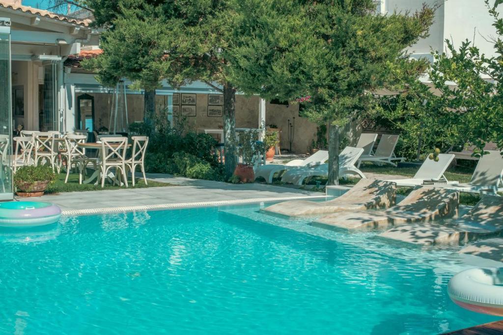 einen Pool mit Stühlen, einem Tisch und Bäumen in der Unterkunft Georgia's Garden by Omilos Hotels in Ammoudara