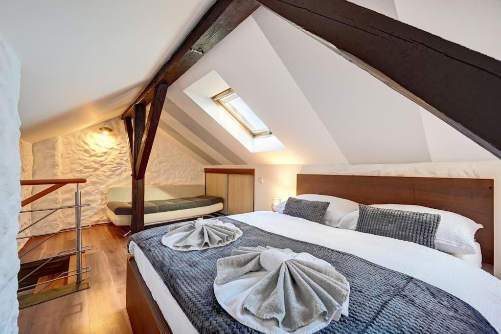 een slaapkamer op zolder met een bed met een handdoek erop bij Velký 3-ložnicový byt Praha 8 Karlín in Praag