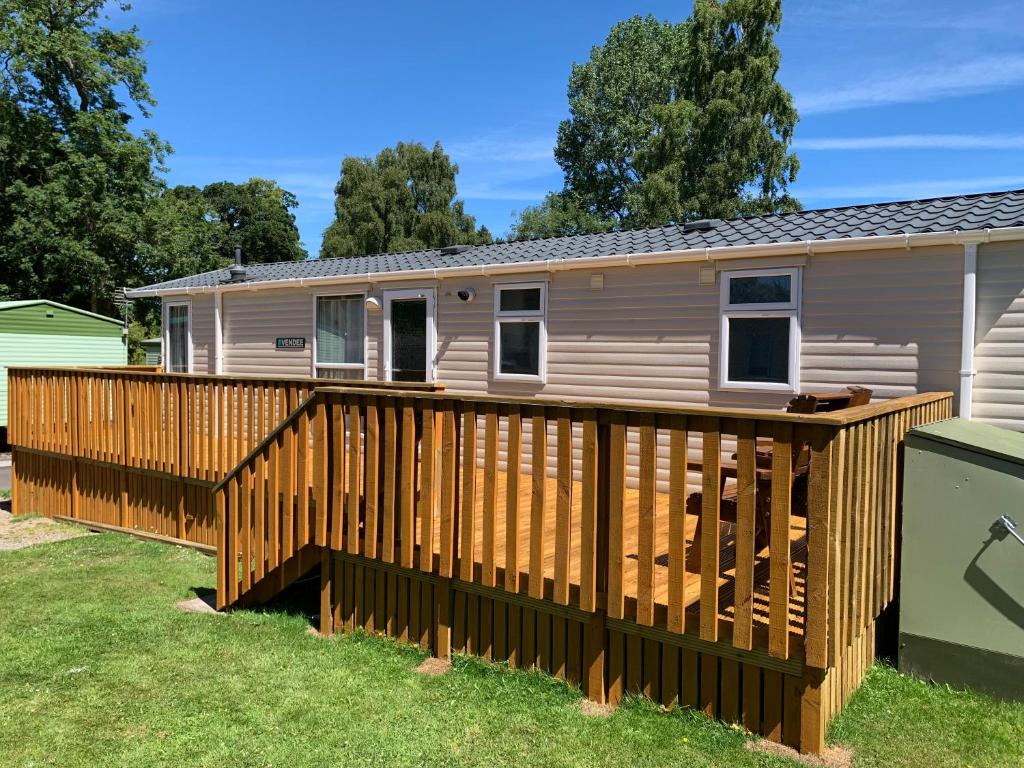 a mobile home with a wooden deck at Devine Staycations at 38 Riverside in Hawick