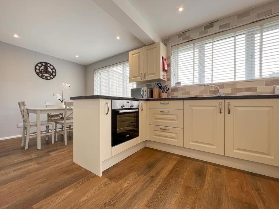a large kitchen with white cabinets and a table at 'Benson View' - 2 bedroom Lake District home in Kendal