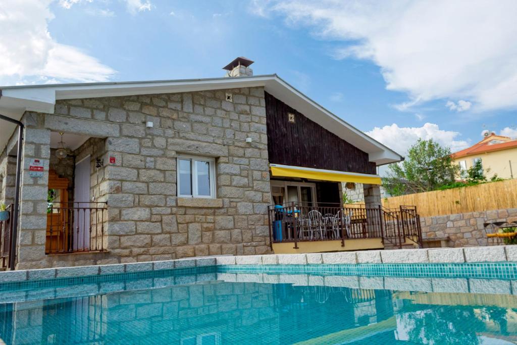 a house with a dog on the roof next to a swimming pool at Casa rural El Abuelo Arturo in Becerril de la Sierra