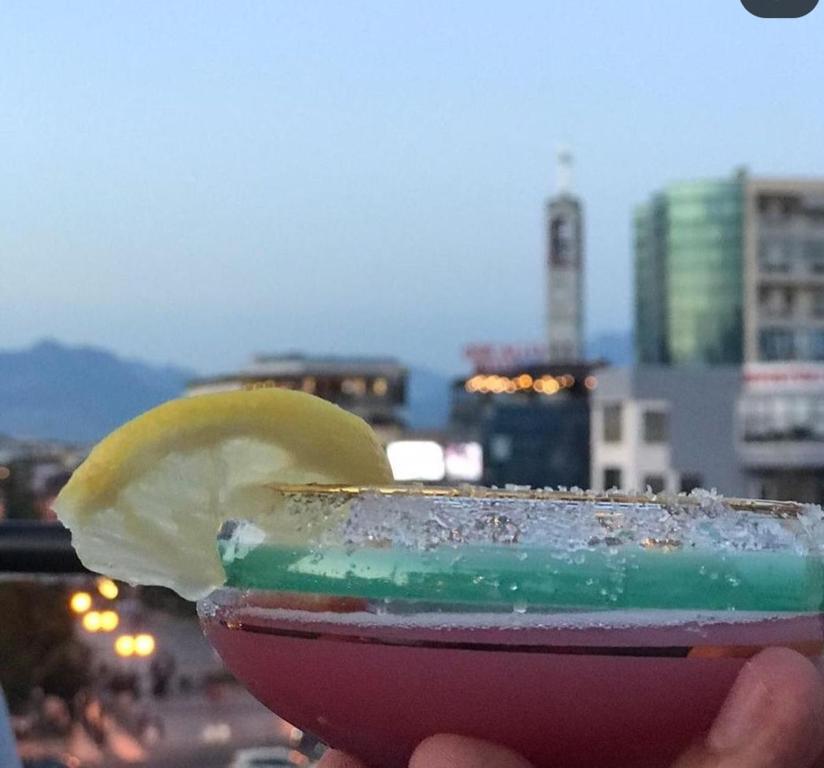 uma pessoa segurando uma bebida com uma fatia de limão em The Rooftop Hostel em Shkodër
