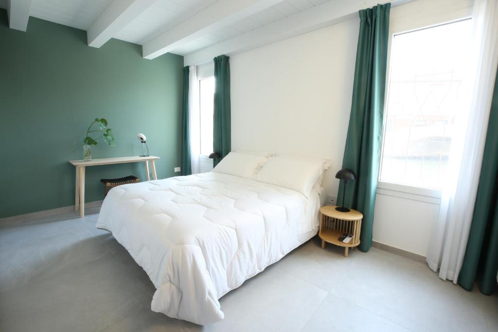 1 dormitorio con cama blanca y ventana grande en AGATOPISTO Animo Salmastro, en Comacchio