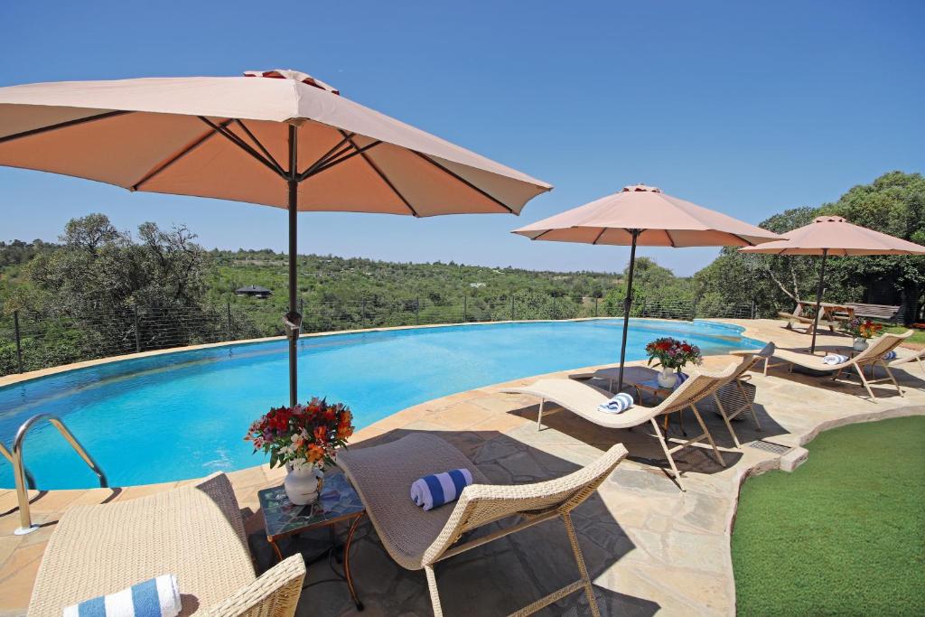 a swimming pool with chairs and umbrellas next to a pool at Olesamara Collection in Nanyuki