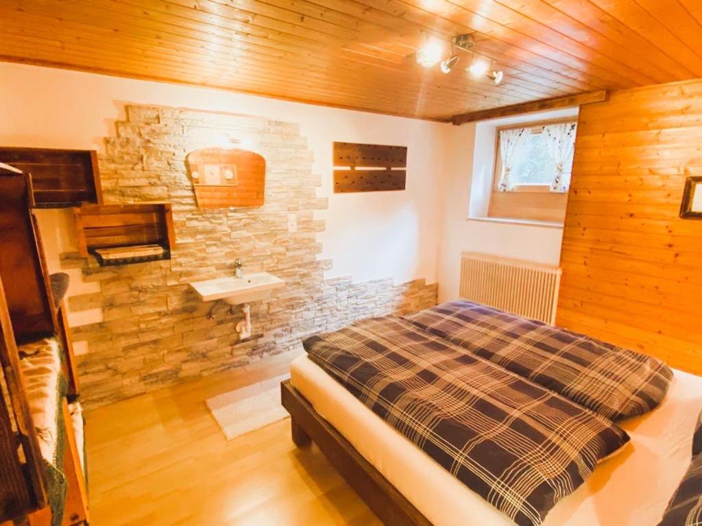 a bedroom with a bed and a stone wall at Ferienwohnung Steinberger in Fügenberg