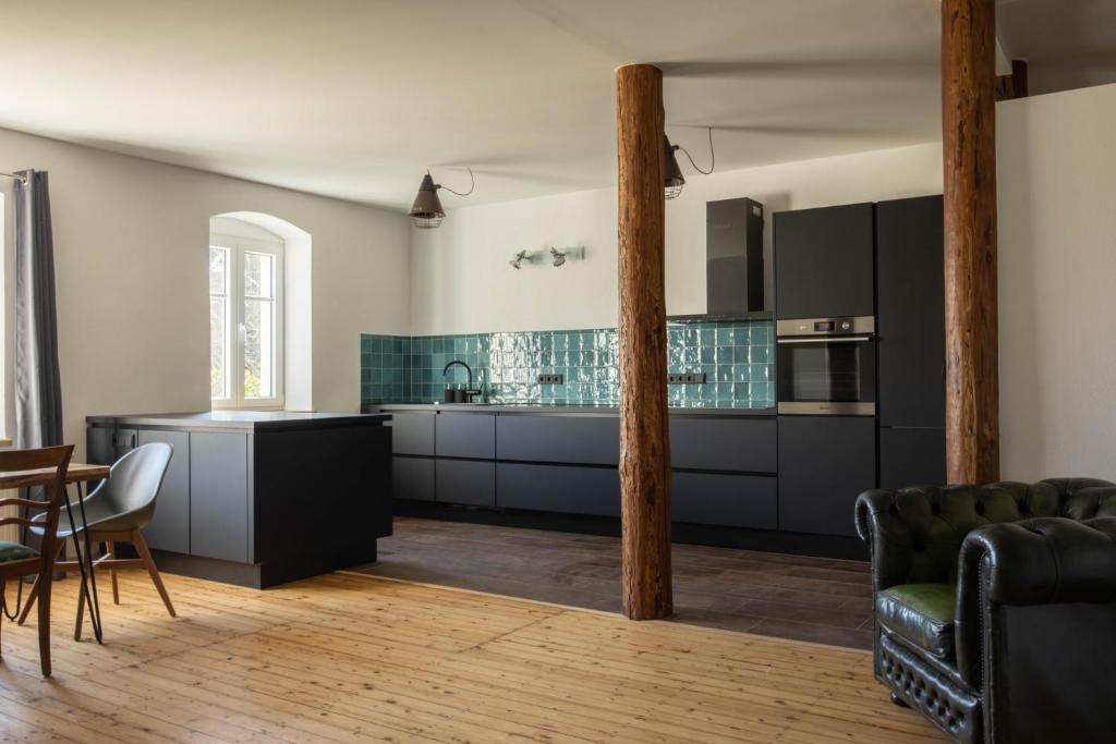 une cuisine avec des armoires noires, une table et des chaises dans l'établissement Designwohnung auf Gutshof mit Sauna zw. L/DD, à Mügeln