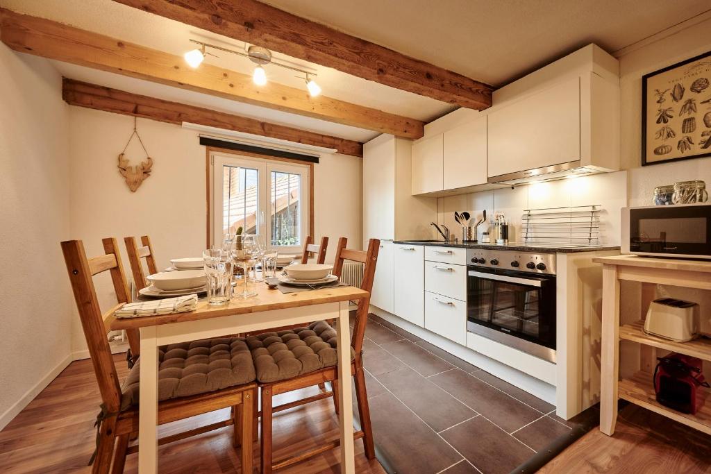 eine Küche mit einem Holztisch, Stühlen und einem Herd in der Unterkunft Lakeside Tiny House Brienz in Brienz