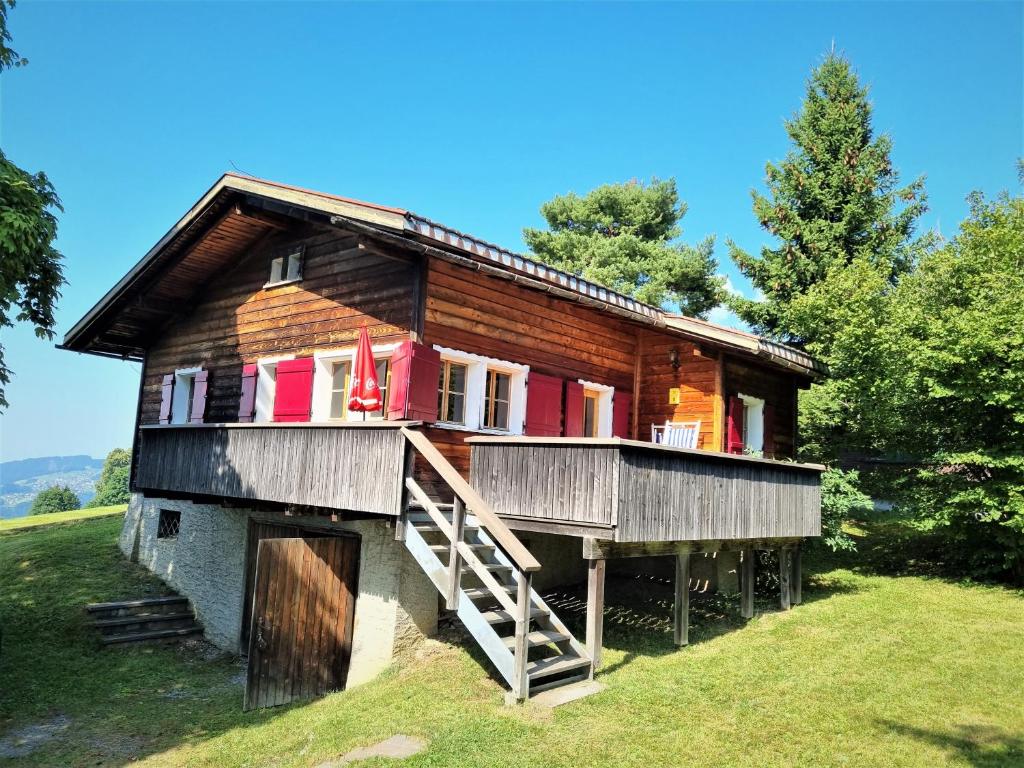 ein Holzhaus auf einem Hügel mit einer Veranda in der Unterkunft Haus Rheintalblick in Übersaxen