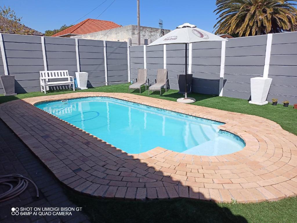 una piscina en un patio con sombrilla en Palm Tree, en Ciudad del Cabo