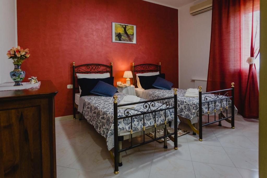 1 dormitorio con 2 camas y pared roja en Casa da Maddalena e Andrea, en Oppeano