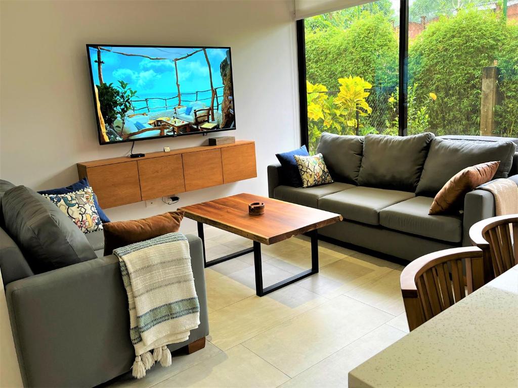 sala de estar con sofá y TV en New! A little piece of Pura Vida - Casa Yara, en Jacó