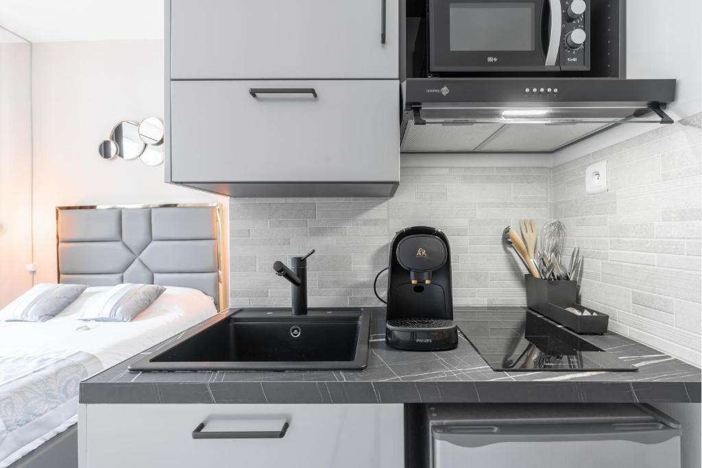 a kitchen with a sink and a microwave and a bed at Studio inspiration hôtel standing Vieux-Port in Marseille