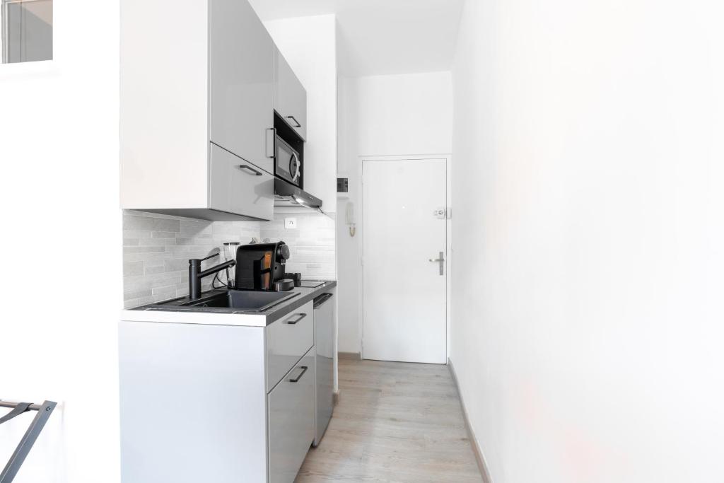 a white kitchen with white cabinets and a sink at Studio inspiration hôtel standing Vieux-Port in Marseille