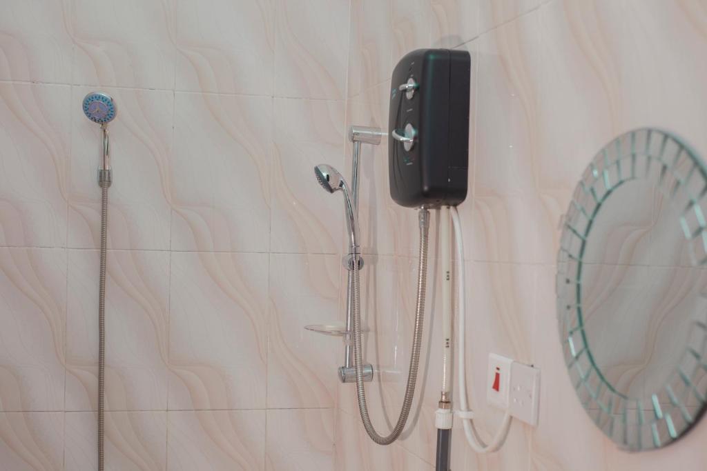 a shower in a bathroom with a phone on the wall at PATAYO LODGE in Bantama