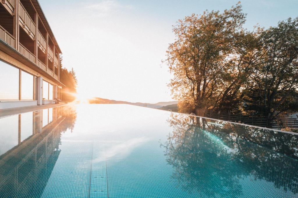 einem Pool vor einem Gebäude mit Sonnenuntergang in der Unterkunft Naturhotel Bauernhofer in Heilbrunn