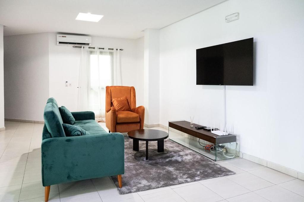 a living room with a couch and a chair and a tv at Sublime appartement à Cocody Riviera Bonoumin . in Abidjan