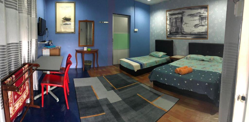 パンタイチェナンにあるWAN'S ROOMSTAY LANGKAWIのベッド2台、デスク、椅子が備わる客室です。
