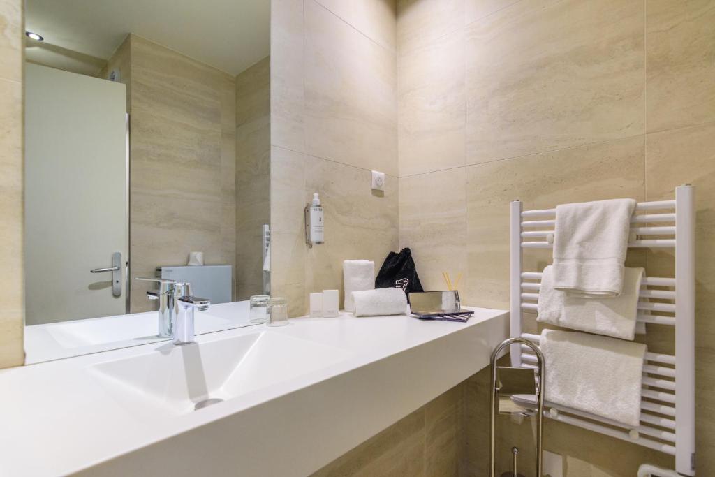 a bathroom with a sink and a mirror and towels at Saint Georges Hotel &amp; Spa in Chalon-sur-Saône
