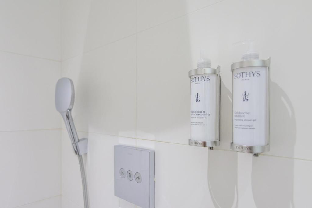 a bathroom with two shampoo bottles on a wall at Saint Georges Hotel &amp; Spa in Chalon-sur-Saône