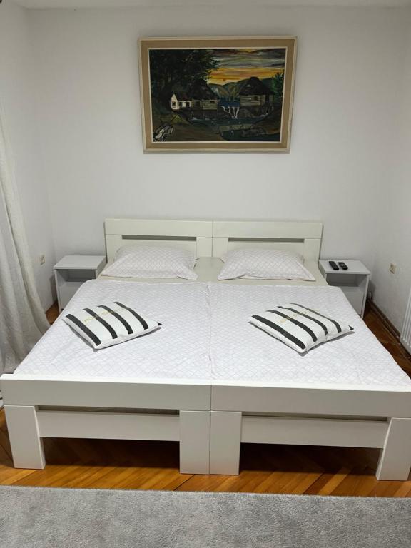 1 cama blanca en un dormitorio con una foto en la pared en Apartman House Jasmina en Bihać