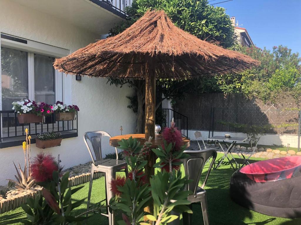 佩皮尼昂的住宿－Au Bougainvillier，庭院配有桌子、遮阳伞和椅子