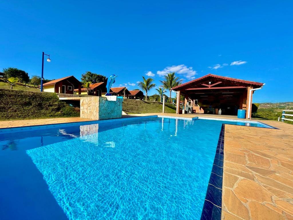 a large blue swimming pool with a gazebo at Chácara com 4 Chalés, grande piscina e muito verde in Atibaia