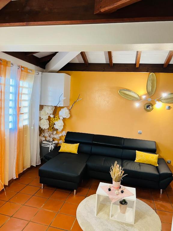 a living room with a black couch and a table at Villa Paradis in Le François