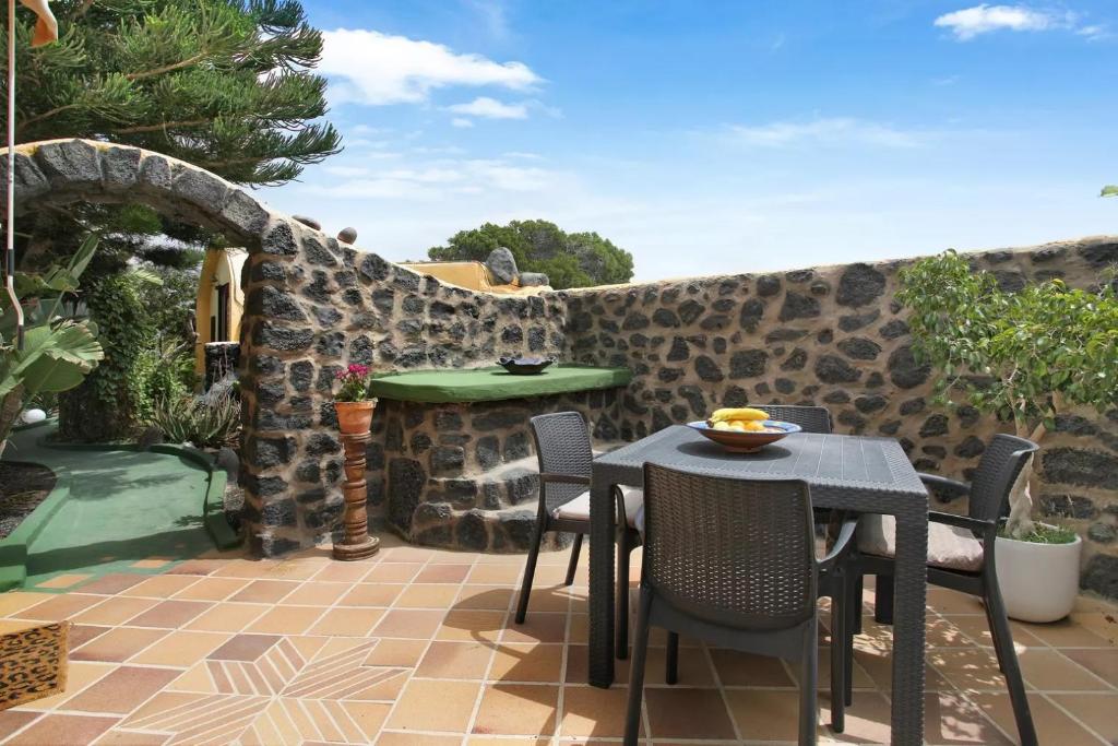 a patio with a table and chairs and a stone wall at Casa Verde in Teguise