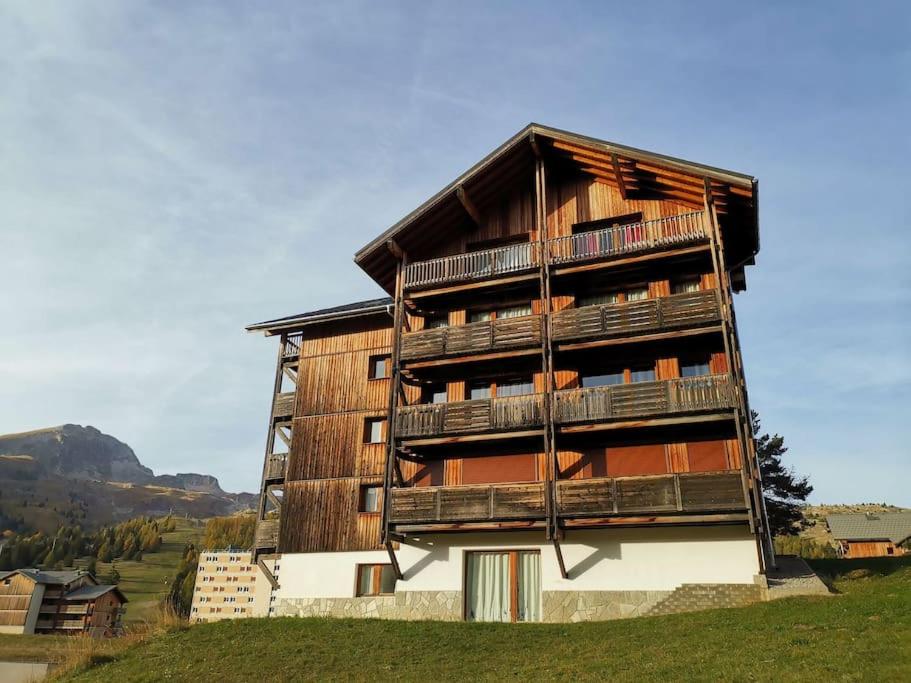 a tall wooden building with balconies on a hill at Appartement cosy dans chalet vue Montagne in Le Dévoluy