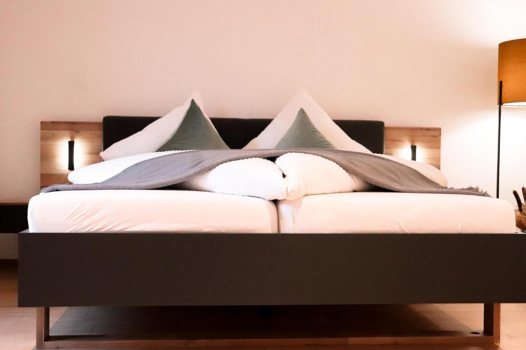 een bed met witte kussens in een kamer bij Imi Appartement in Eben im Pongau