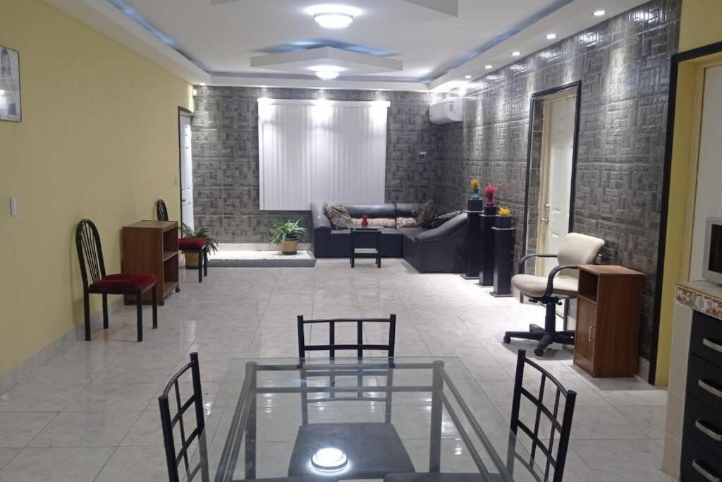 - un salon avec une table et des chaises en verre dans l'établissement Acogedor departamento en el centro de la ciudad, à Reynosa