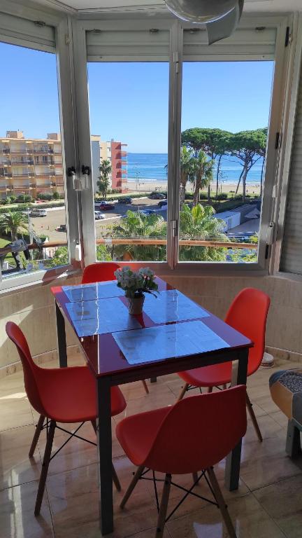 mesa de comedor con sillas rojas y vistas al océano en Promar en La Pineda