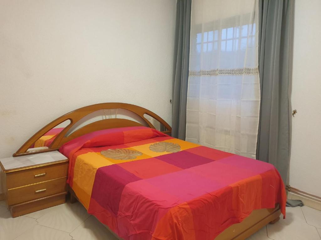 Un dormitorio con una cama colorida y una ventana en Hermosa Habitación A individual. Getafe centro.Cerca del metro y Renfe en Getafe
