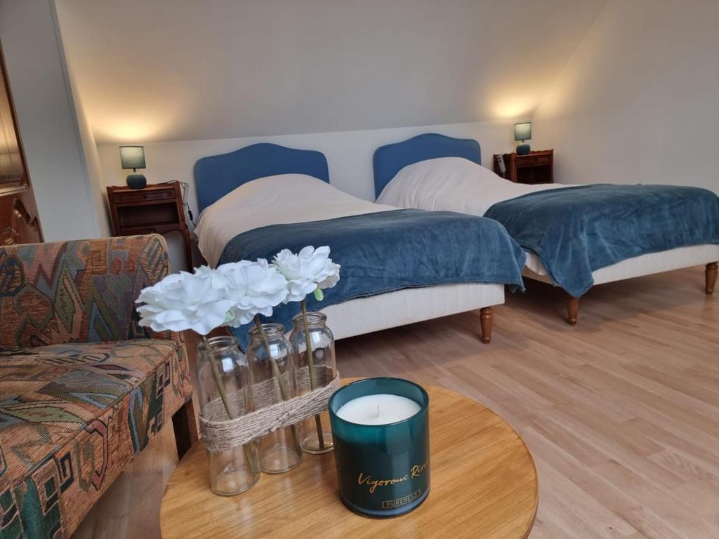 una habitación con 2 camas y una mesa con una vela en Le Vivien, en Romorantin-Lanthenay