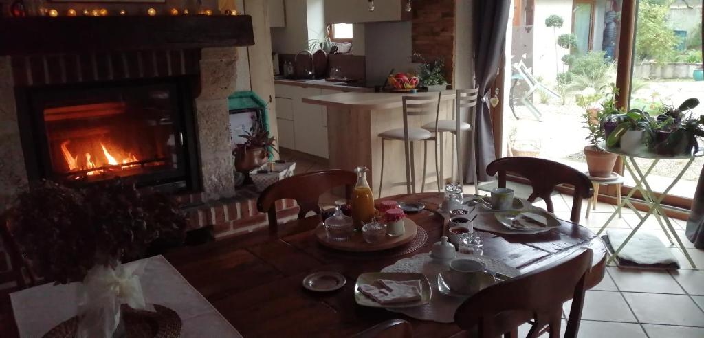 a table and chairs in a kitchen with a fireplace at L&#39;Orme Seul, Maison d&#39;hôtes in Vineuil