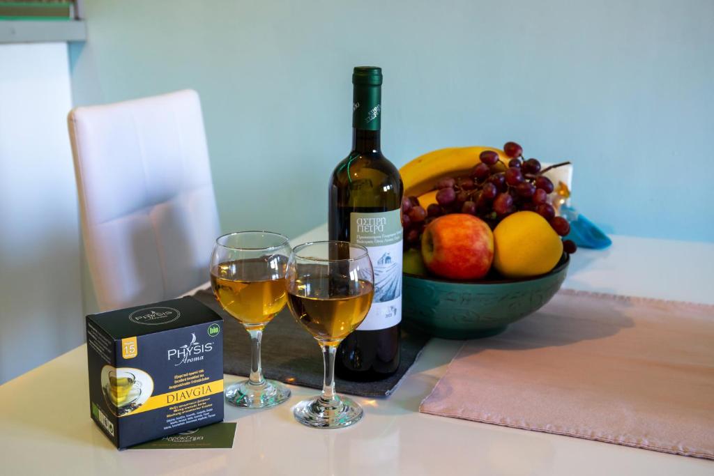 a bottle of wine and two glasses of white wine and a bowl of fruit at The North Apartment in Kastoria