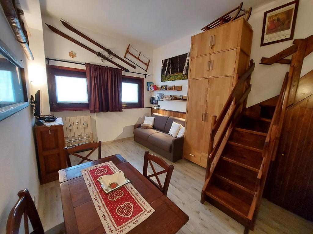 ein Wohnzimmer mit einem Sofa, einem Tisch und einer Treppe in der Unterkunft Le Petit Refuge Cervinia in Breuil-Cervinia