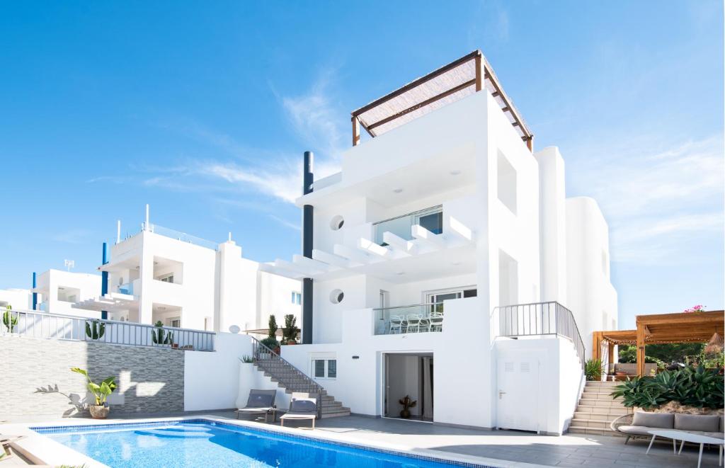 a white house with a swimming pool in front of it at Villa Vidal in Sant Josep de sa Talaia