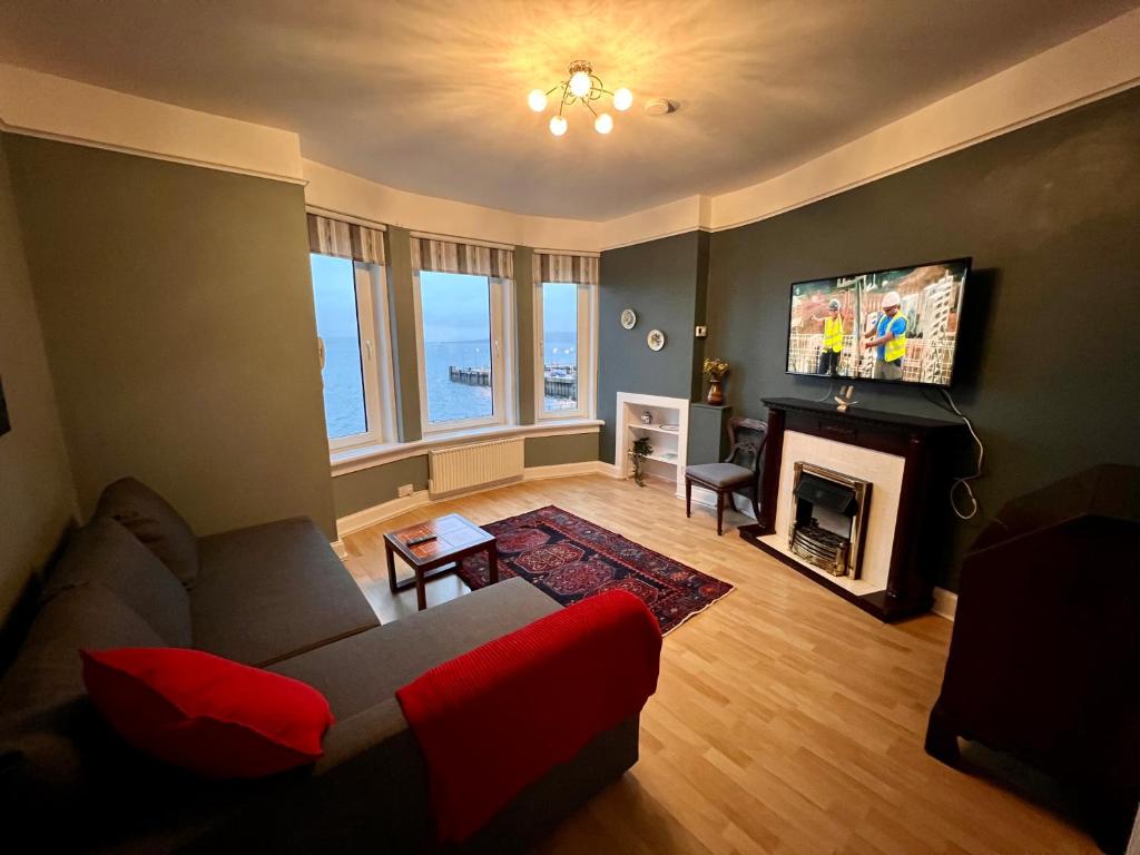 a living room with a couch and a fireplace at Anchorage, a lovely 2nd floor one bedroom apartment with fabulous seaviews in Largs