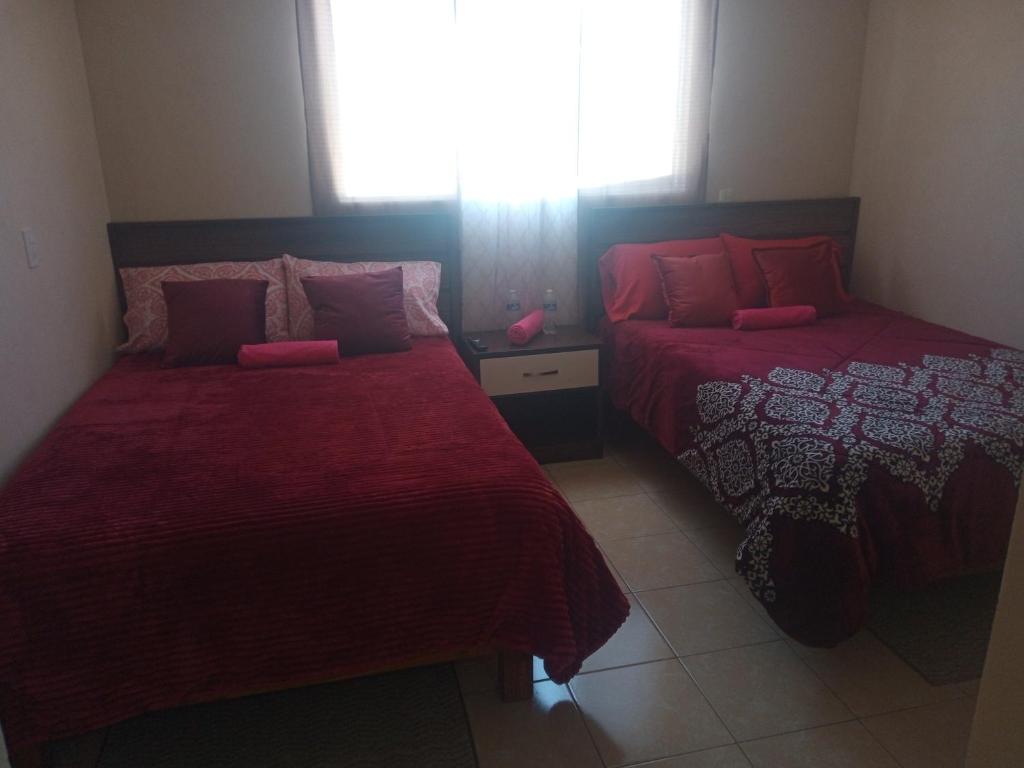 um quarto com 2 camas com lençóis vermelhos e uma janela em La casa de las flores em Zacatlán