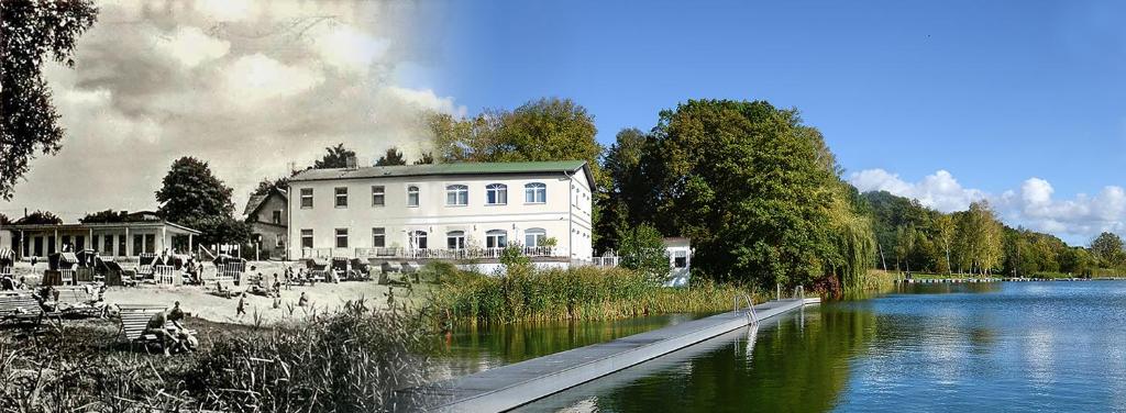 ein großes weißes Gebäude neben einem Fluss mit einem Gebäude in der Unterkunft Hotel & Restaurant Haus am See in Löcknitz