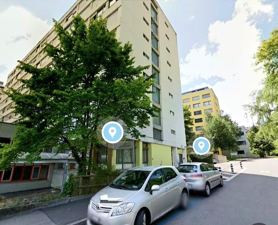 dos autos estacionados en una calle al lado de un edificio en Apartment Zentrum Bern Marzili en Berna