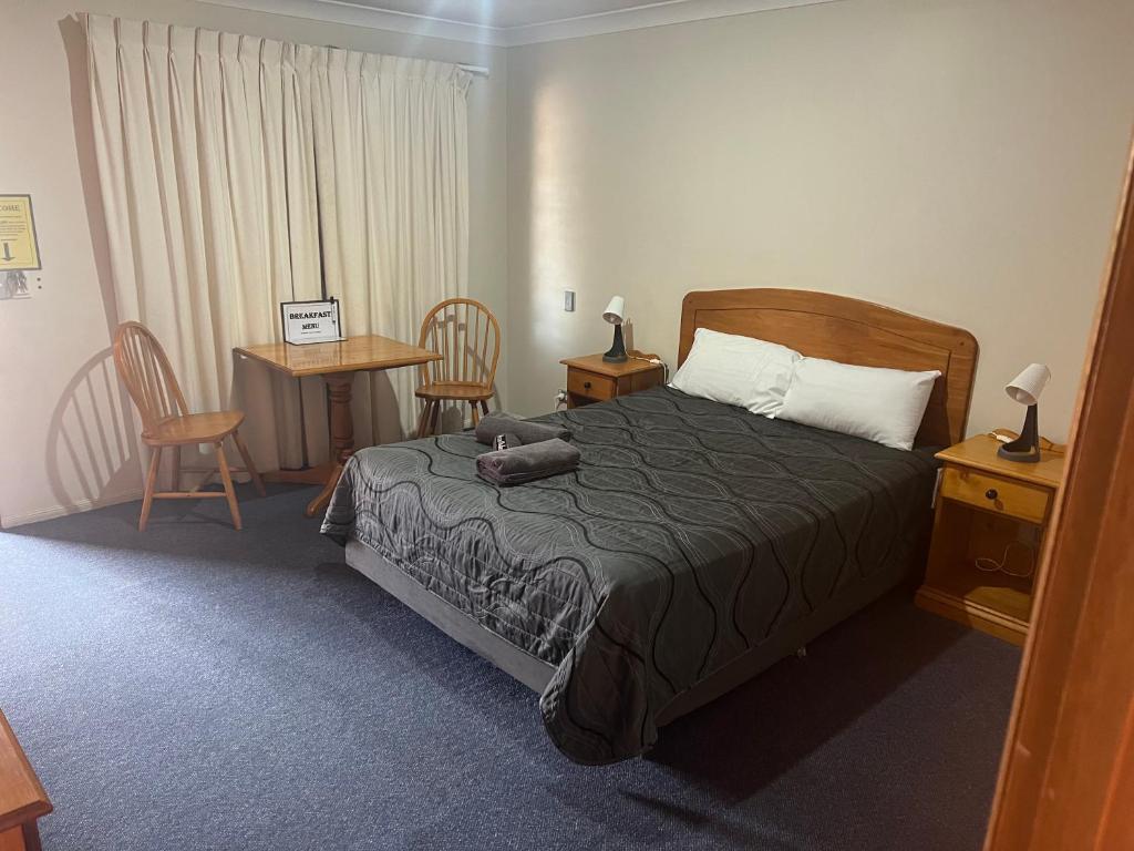 1 dormitorio con 1 cama, mesa y sillas en Asters On James Motor Inn, en Toowoomba