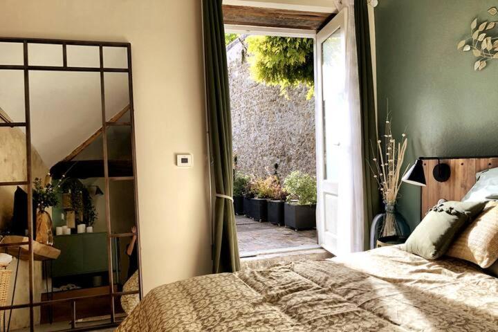 een slaapkamer met een bed en een glazen schuifdeur bij NATICOSY-Appartement centre historique avec jardin IDEAL COUPLE in Bellême