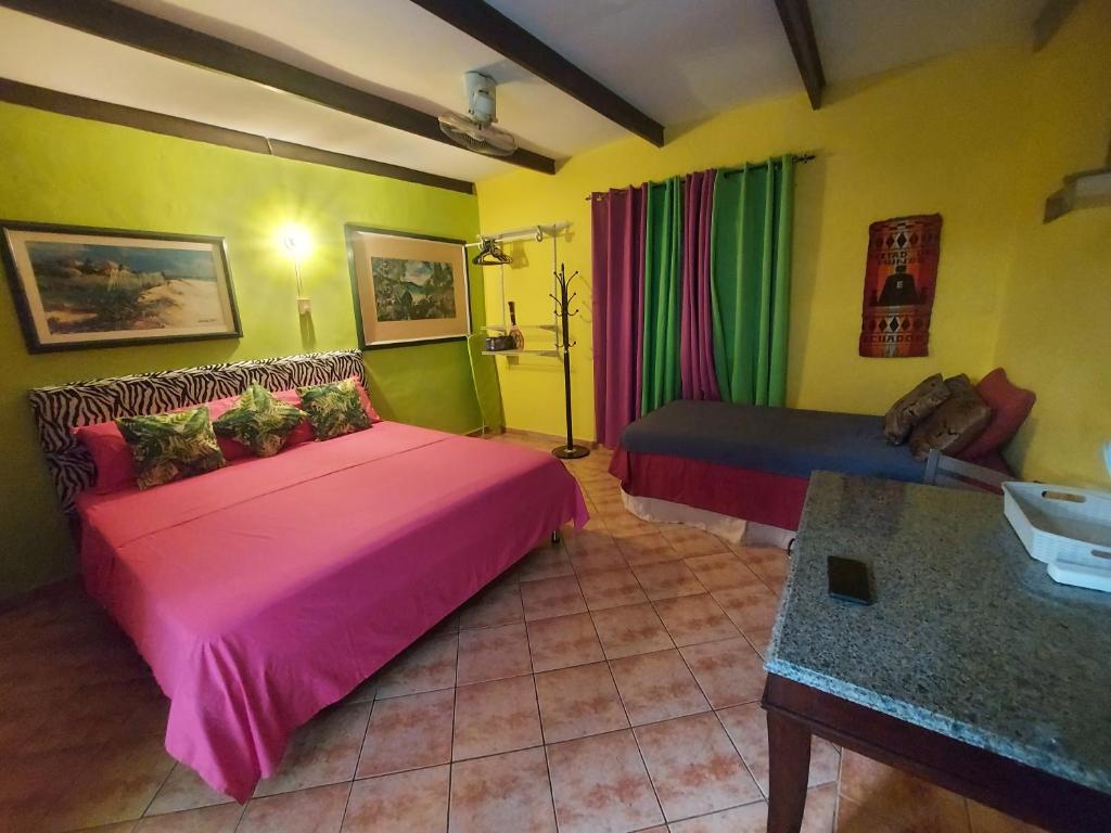 1 dormitorio con cama rosa y sofá en Terrakota Apartments, en Willemstad