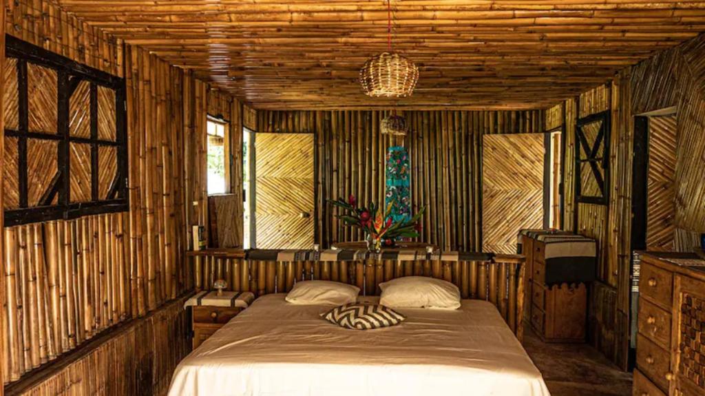 a bedroom with a bed in a room with wooden walls at Finca Vista Hermosa - Deluxe Bamboo Cabana in Pluma Hidalgo